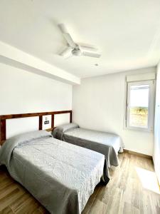 two beds in a room with a ceiling fan at Casa Rural MaciasDehesa in Merida