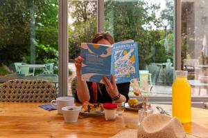 a woman sitting at a table reading a book at Hôtel 96 in Marseille