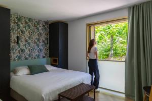 a woman looking out the window of a bedroom at Hôtel 96 in Marseille