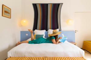 a woman laying on a bed reading a book at Hôtel 96 in Marseille