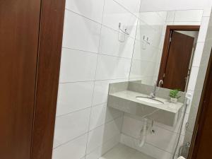 a white bathroom with a sink and a mirror at Madeira Lofts - Centro Juina in Juína