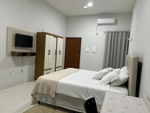 a white bedroom with a bed and a tv at Madeira Lofts - Suite 03 Centro in Juína