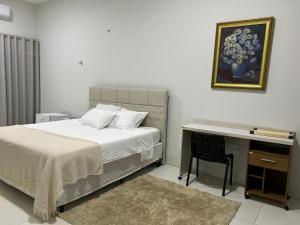 a bedroom with a bed and a desk with a picture at Madeira Lofts - Suite 03 Centro in Juína