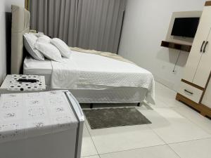 a white bedroom with a bed and a television at Madeira Lofts - Suite 03 Centro in Juína