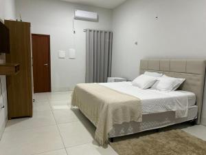 a white bedroom with a bed and a television at Madeira Lofts - Suite 03 Centro in Juína