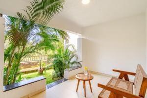 a room with a table and a palm tree at Susegad Suites Arpora Apartments & Villas with Reserved Parking in Arpora