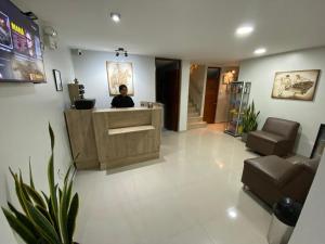 a person sitting at a reception desk in a lobby at Hotel Begonias in Chiclayo