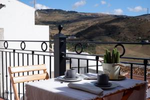 a table with plates and cups and a cactus on a balcony at Casa Frasquita del Pan - Caminito del Rey in Valle de Abdalagís