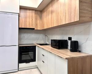 cocina con electrodomésticos blancos y encimera de madera en Raimbek19-45 Residence 1BR nearby metro & drinking water as a gift, en Almaty
