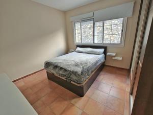 a small bedroom with a bed and two windows at Esencia de Sal in San Antonio