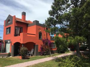 a red house with a tree in front of it at Complejo Pueblo del Sol in Piriápolis