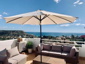 - une terrasse avec 2 canapés et un parasol dans l'établissement Dreamy Sea View Apartment with Access to Private Pool & Stunning Rooftop, à Luz