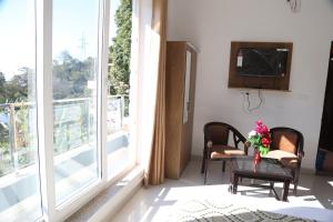 un soggiorno con una grande finestra e un tavolo con fiori di Hotel yog tapovan MOUNTAIN VIEW ROOM a Rishikesh Altre 2 foto