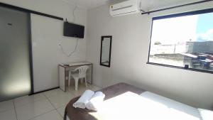 a bedroom with a bed and a table and a window at Pousada La Ville in Itapetinga