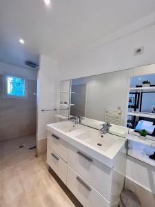 昂叙埃拉雷东Appartement "Calanques" - Domaine Ciel et Mer的带两个水槽和一面镜子的白色浴室