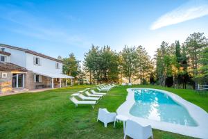a group of chairs sitting next to a swimming pool at Villa ai Caprioli Mondaino in Mondaino