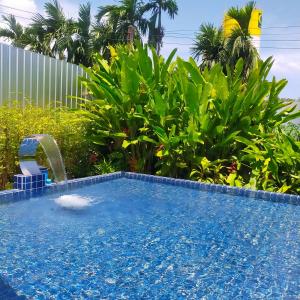 a swimming pool with a water fountain in a yard at Davy Cottage Phuket in Ban Riang