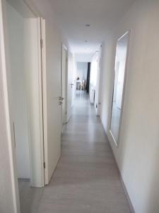 a long hallway with white walls and a mirror at Gemeinschaftsapartment 8 - Ferienwohnung Ottendorf-Okrilla in Ottendorf-Okrilla
