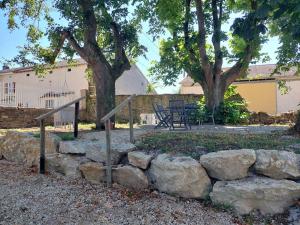 a stone retaining wall with a fence and a tree at Le château d'Aude in Gironcourt-sur-Vraine