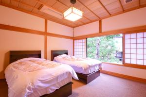 two beds in a room with two windows at Koyasan Shukubo Saizenin in Koyasan