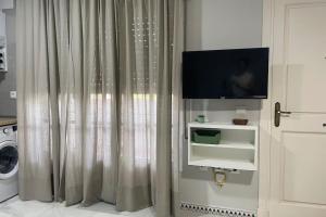 een woonkamer met een televisie en een gordijn bij Apartamento La Barrosa Beach in Novo Sancti Petri