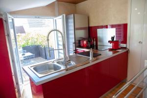 a red kitchen with a sink and a window at La Petite Maison de Jane in Reims
