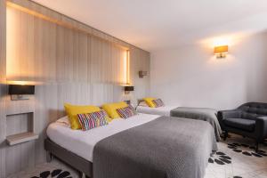 a hotel room with two beds and a chair at Le Cornouaille Hotel & Spa in Bénodet +37 photos