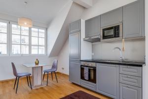 a kitchen with white cabinets and a table and chairs at Pétrusse Élite Suites - Elegant Suites Luxembourg City Center in Luxembourg