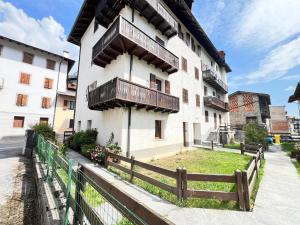 a building with a wooden fence in front of it at Condominio Le Dolomiti in Forni di Sotto