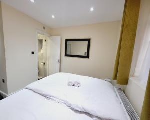 a bedroom with a white bed with two shoes on it at Nest & Rest En-Suite in Ashford +6 photos