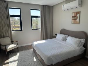 a bedroom with a bed and a chair and windows at لوقانو فيلا Lugano Villa in Hail +12 photos