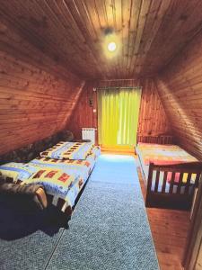 a bedroom with two beds in a wooden cabin at Vikendica Luna in Gornja Šišava