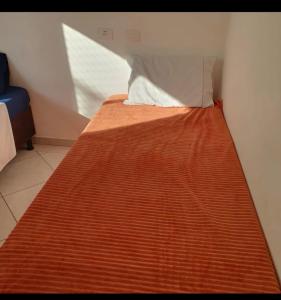 a bed in a room with a pillow on it at 50 m do mar, 3 dorm, sacada com vista mar, pitangueiras, vaga de garagem, Pet friendly, berço in Guarujá