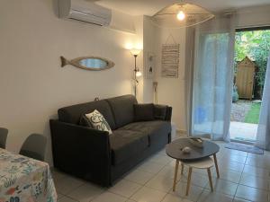 un salon avec un canapé et une table dans l'établissement Appartement 4 étoiles avec jardin clôturé et piscine dans la résidence - Narbonne Plage, à Narbonne