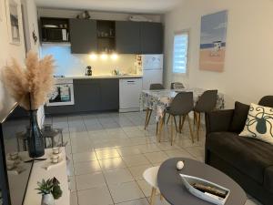 un salon et une cuisine avec un canapé et une table dans l'établissement Appartement 4 étoiles avec jardin clôturé et piscine dans la résidence - Narbonne Plage, à Narbonne 16 autres photos