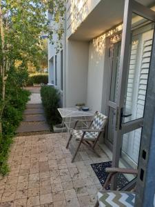 a patio with a table and a chair on a house at Nerf-af ROOMS and Cottage at Onrus , Hermanus in Hermanus +22 photos