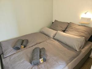 a bed with grey blankets and pillows on it at Like at home - moderne Wohnung in Königsbrunn - 30qm - Netflix in Königsbrunn