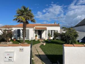 a white house with a palm tree in the yard at Charmante et accueillante maison in Saint-Pierre-dʼOléron