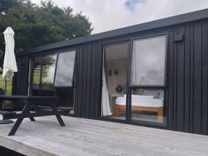 ein schwarzer Schiffscontainer mit einem Bett auf dem Deck in der Unterkunft Twin Totara Cottage in Mangawhai