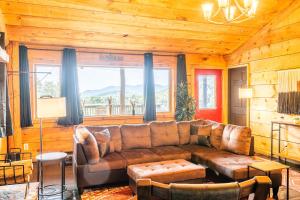 a living room with a leather couch and a large window at Lodge Cabin Feed Brush Horses Mountain View Hot Tub Fireplace in Boone