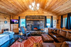 a living room with a stone fireplace in a cabin at Lodge Cabin Feed Brush Horses Mountain View Hot Tub Fireplace in Boone