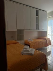 two beds in a room with white cabinets and towels at La Casa per te in Pescara