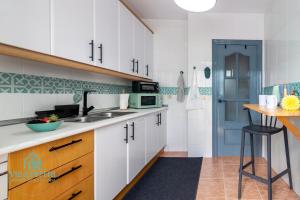 a kitchen with white cabinets and a blue door at Villa Pepita in Almerimar