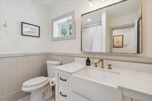 Un baño con lavabo, inodoro y espejo. en All Sports Lake House on Lake Orion!, en Lake Orion Heights