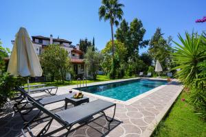 a swimming pool with two chairs and an umbrella at Villa Misli - red/ green in Dalyan