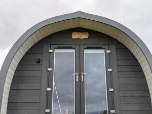 a building with a door with a sign above it at Robins Nest Pod in Breakish