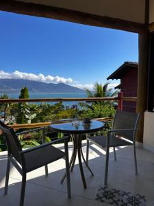 a table and chairs on a balcony with a view at Pousada Mariola in Ilhabela