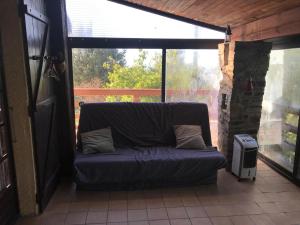 a couch sitting in a screened in porch at La Petite Maison sur la Colline in Chassiers