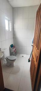 a bathroom with a toilet in a white tiled room at Casa praia in Peruíbe