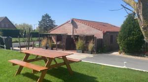 un tavolo da picnic sull'erba di fronte a una casa di Charmant logement tout confort avec terrasse a Saint-Amand-les-Eaux